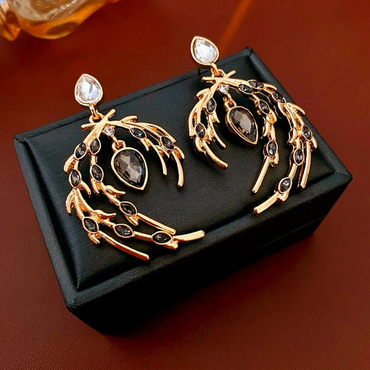 Model showcasing the dangle and style of the 14K Gold-Plated Diamond Feather Earrings