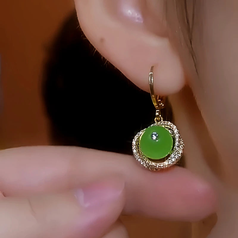 Model showcasing the dangle and style of the 14K Gold-Plated Diamond Green Bead Spiral Earrings