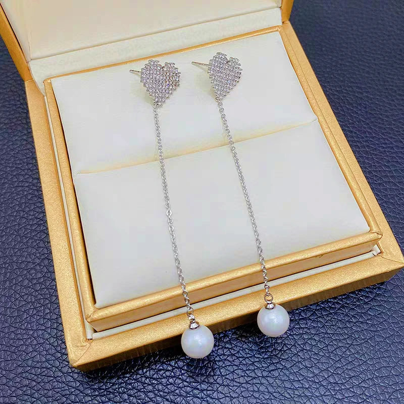 Angled view of the 14K Gold-Plated Diamond Heart Pearl Tassel Earrings