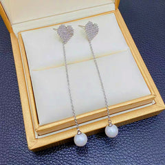 Angled view of the 14K Gold-Plated Diamond Heart Pearl Tassel Earrings