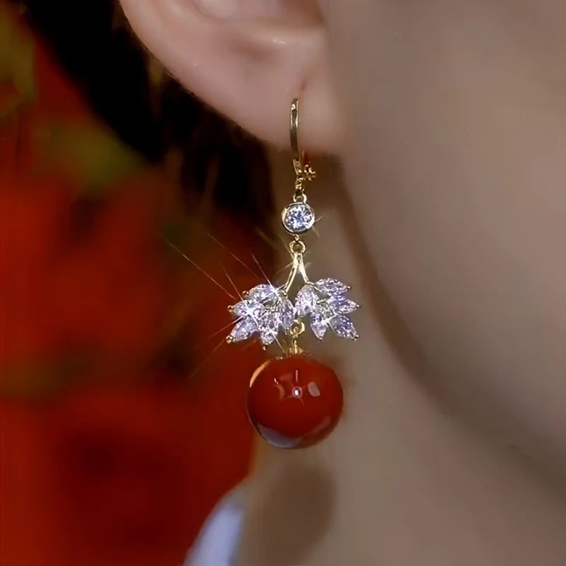 Model showcasing the dangle and style of the 14K Gold-Plated Diamond Leaf Red Pearl  Earrings