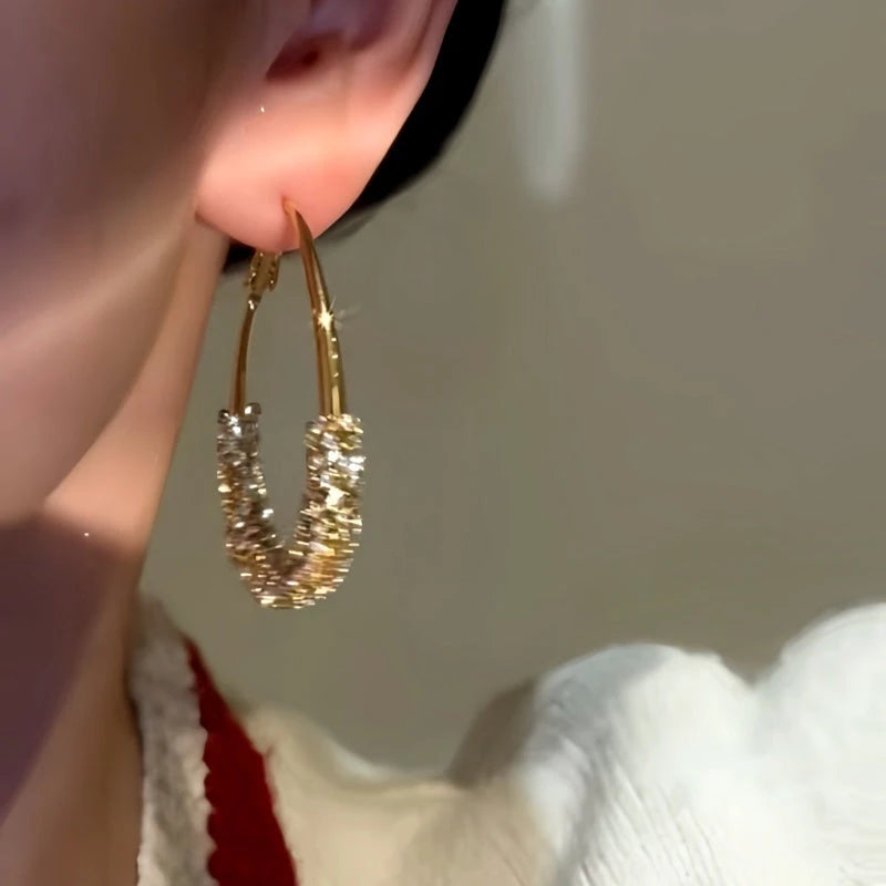 Model showcasing the dangle and style of the 14K Gold-Plated Diamond Oval Hoop Earrings