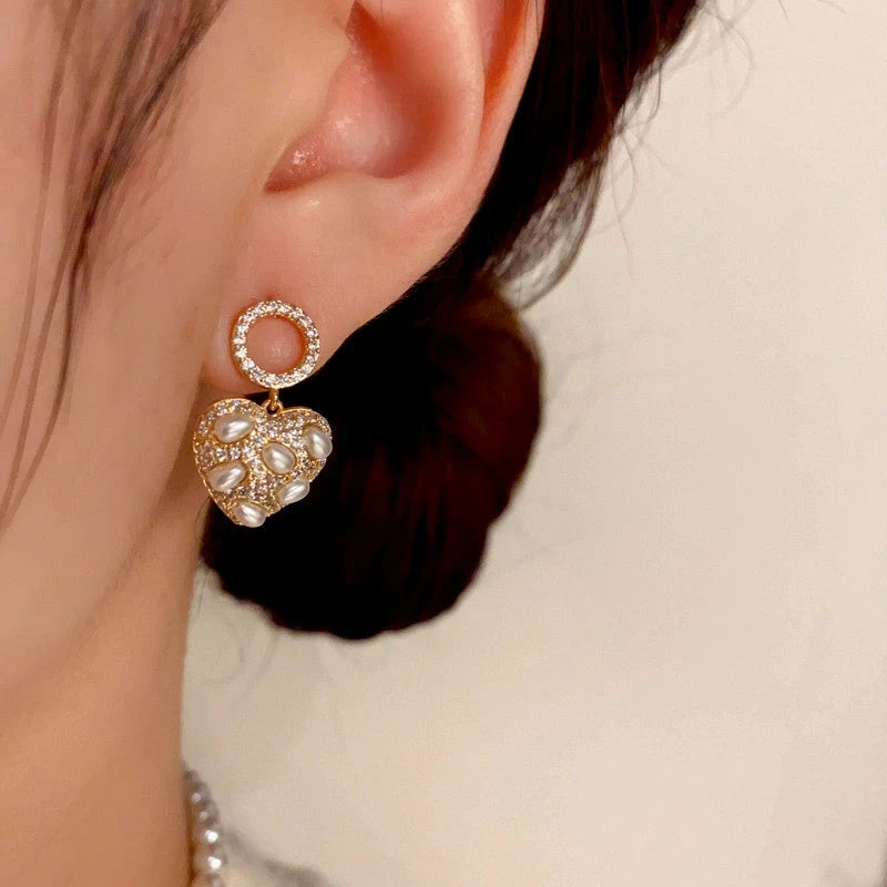 Model showcasing the dangle and style of the 14K Gold-Plated Diamond Pearl Heart Earrings