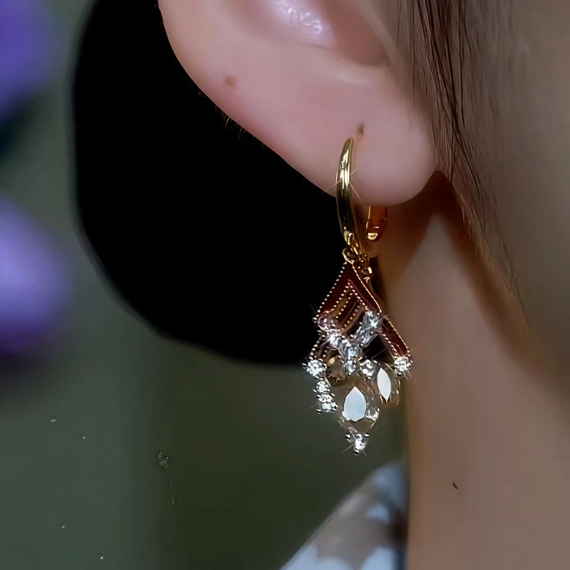 Model showcasing the dangle and style of the 14K Gold-Plated Double-Layer Oil Drop Diamond And Crystal Tassel Earrings