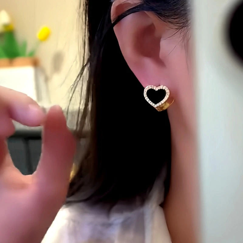 Model showcasing the dangle and style of the 14K Gold-Plated Double-Sided Black And White Heart Earrings