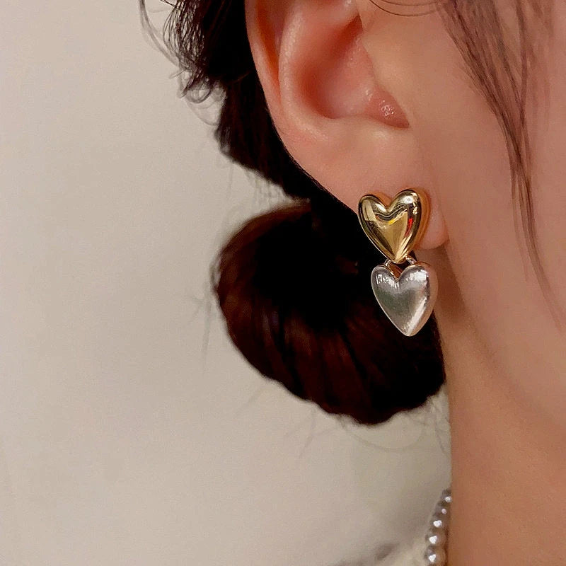 Model showcasing the dangle and style of the 14K Gold-Plated Double Heart Earrings