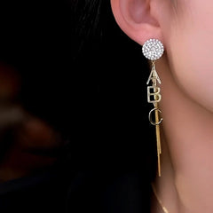 Model showcasing the dangle and style of the 14K Gold-Plated Elegant AB Style Asymmetrical Letter Tassel Earrings