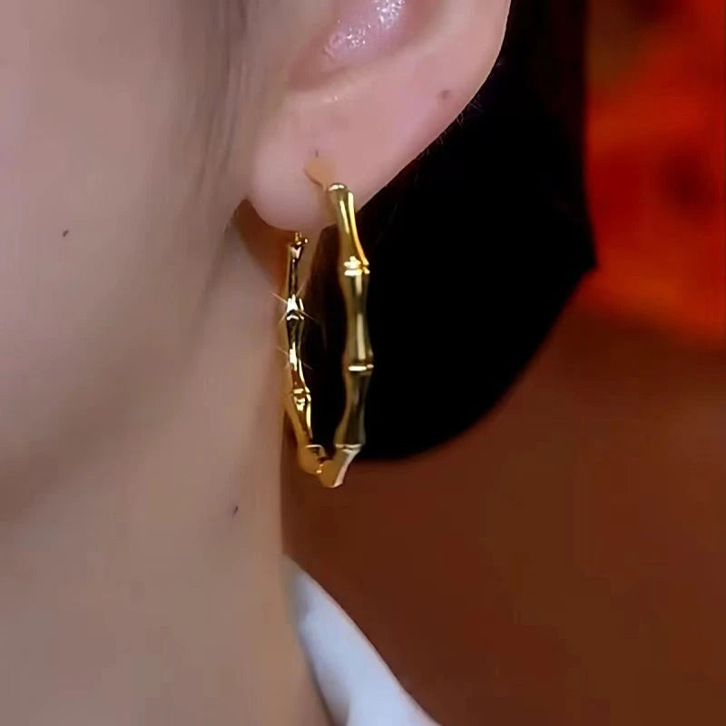 Model showcasing the dangle and style of the 14K Gold-Plated Elegant Bamboo Exaggerated Large Hoop Earrings