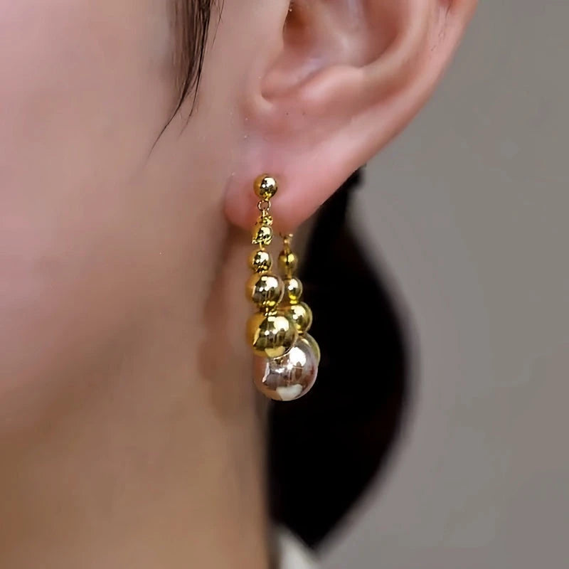 Model showcasing the dangle and style of the 14K Gold-Plated Elegant Bead Earrings
