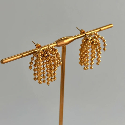Model showcasing the dangle and style of the 14K Gold-Plated Elegant Beaded Tassel Earrings
