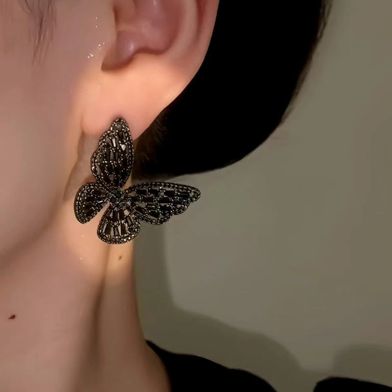 Model showcasing the dangle and style of the 14K Gold-Plated Elegant Black Butterfly Earrings