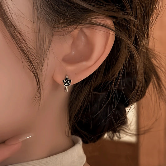 Model showcasing the dangle and style of the 14K Gold-Plated Elegant Black Rose Hoop Earrings
