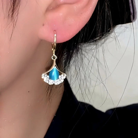 Model showcasing the dangle and style of the 14K Gold-Plated Elegant Blue Cat's Eye Stone Ginkgo Leaf Earrings