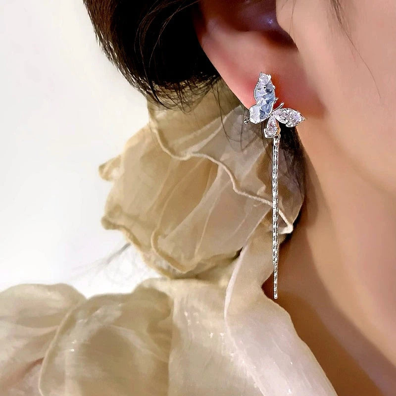 Model showcasing the dangle and style of the 14K Gold-Plated Elegant Blue Crystal Butterfly Earrings