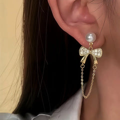Model showcasing the dangle and style of the 14K Gold-Plated Elegant Bow And Heart Earrings