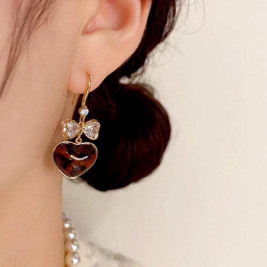 Model showcasing the dangle and style of the 14K Gold-Plated Elegant Bow Leopard Heart Ear Hooks
