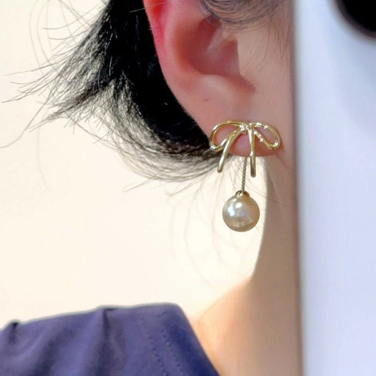 Model showcasing the dangle and style of the 14K Gold-Plated Elegant Bow Pearl Jacket Earrings