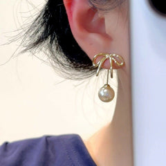 Model showcasing the dangle and style of the 14K Gold-Plated Elegant Bow Pearl Jacket Earrings
