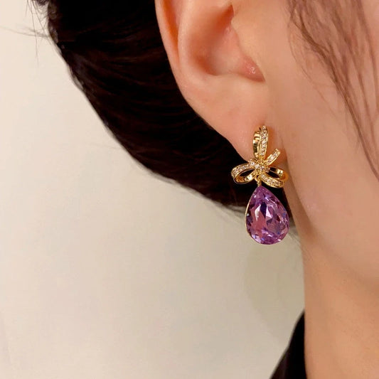Model showcasing the dangle and style of the 14K Gold-Plated Elegant Bow Purple Diamond Water Drop Earrings