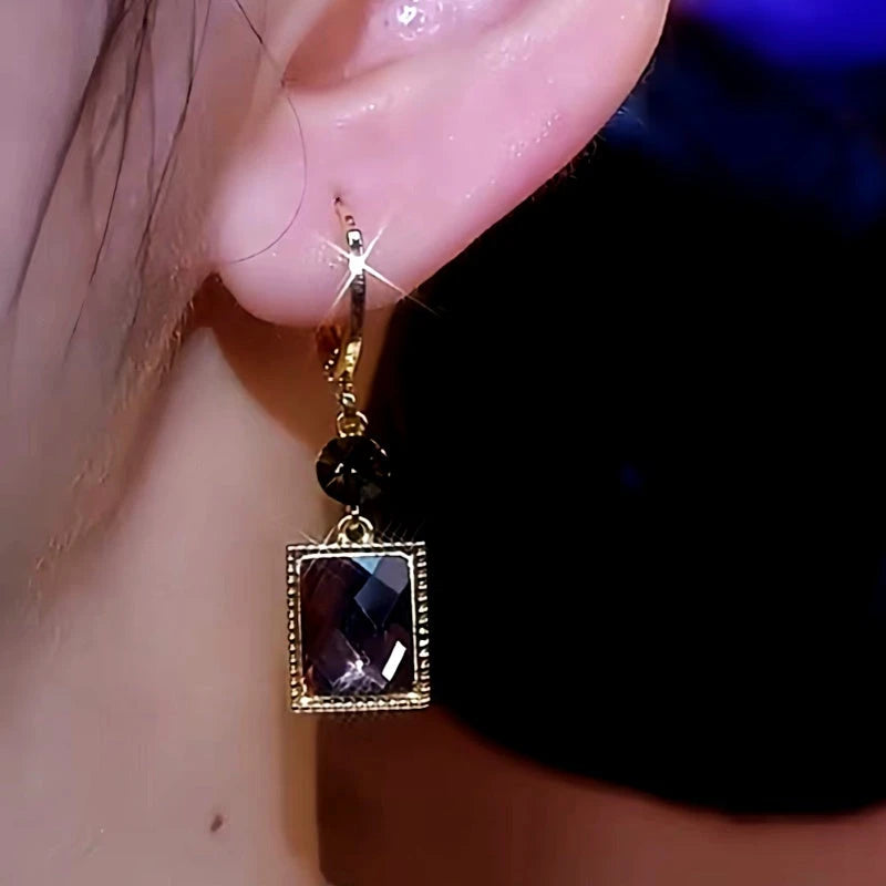 Model showcasing the dangle and style of the 14K Gold-Plated Elegant Brown Zircon Geometric Cube Earrings