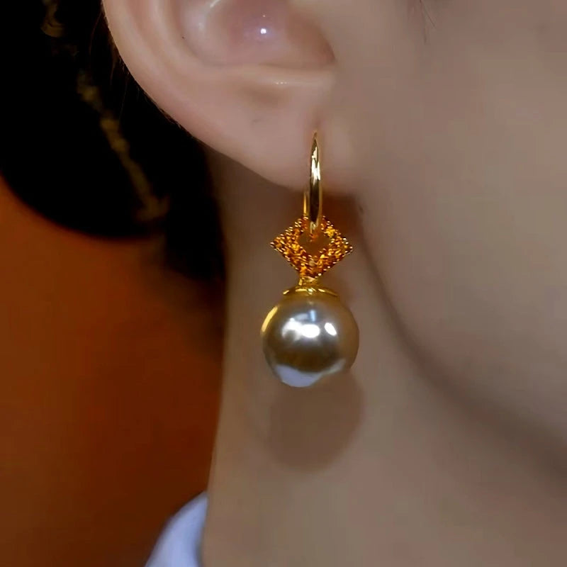 Model showcasing the dangle and style of the 14K Gold-Plated Elegant Brown Zircon Pearl Earrings