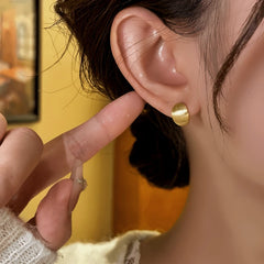 Model showcasing the dangle and style of the 14K Gold-Plated Elegant Brushed Geometric Hoop Earrings