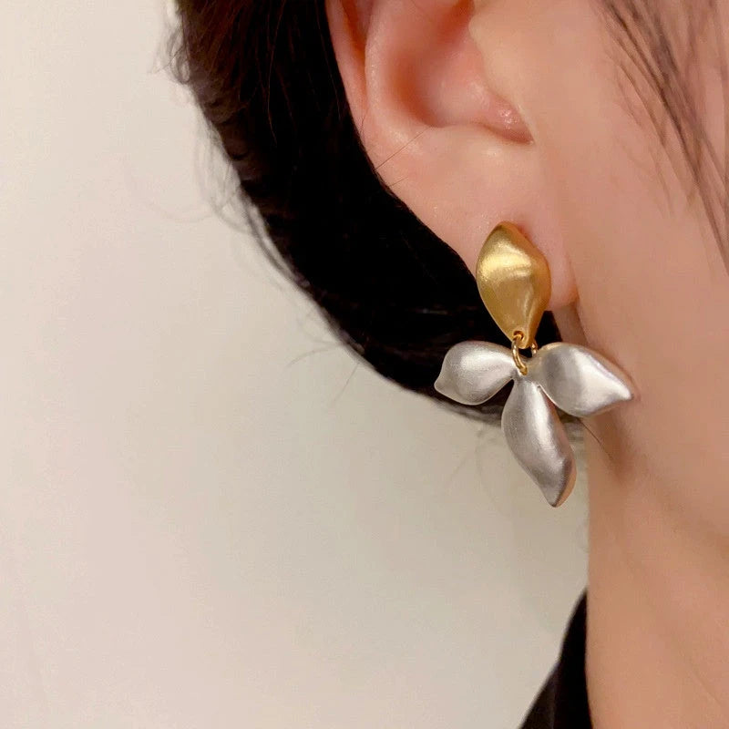 Model showcasing the dangle and style of the 14K Gold-Plated Elegant Brushed Gold And Silver Contrast Leaf Earrings