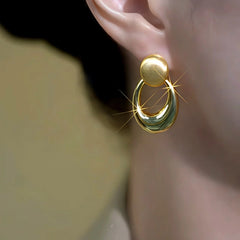 Model showcasing the dangle and style of the 14K Gold-Plated Elegant Brushed Oval Earrings