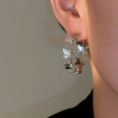 Model showcasing the dangle and style of the 14K Gold-Plated Elegant Butterfly Hoop Earrings