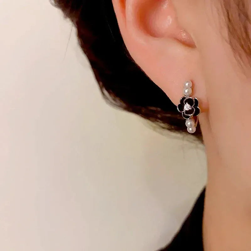 Model showcasing the dangle and style of the 14K Gold-Plated Elegant Camellia Pearl Hoop Earrings