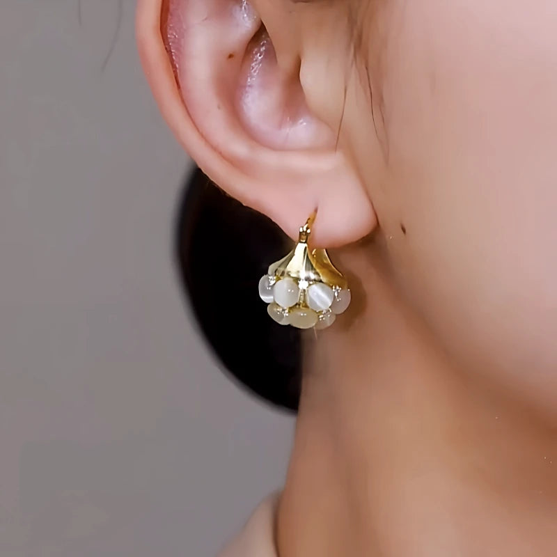 Model showcasing the dangle and style of the 14K Gold-Plated Elegant Cat's Eye Stone Basket Earrings