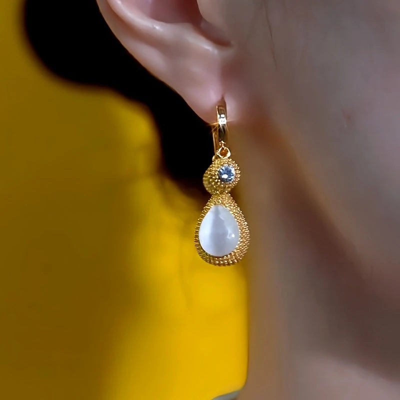 Model showcasing the dangle and style of the 14K Gold-Plated Elegant Cat's Eye Stone Durian Tassel Earrings