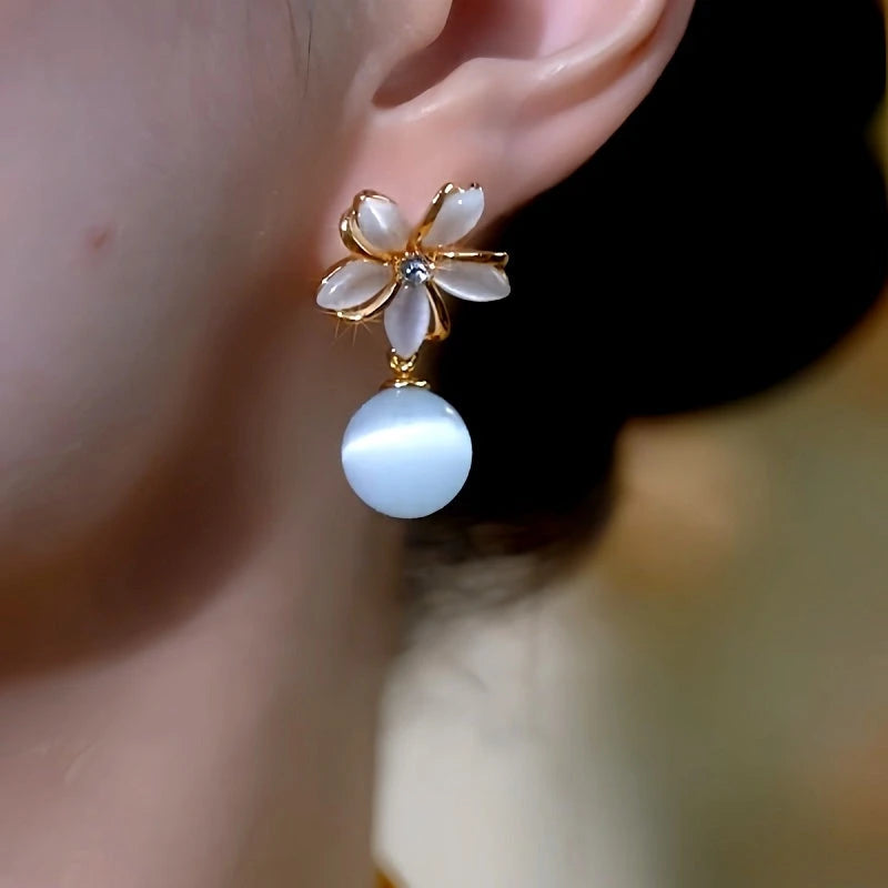 Model showcasing the dangle and style of the 14K Gold-Plated Elegant Cat's Eye Stone Flower Bead Earrings