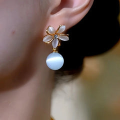 Model showcasing the dangle and style of the 14K Gold-Plated Elegant Cat's Eye Stone Flower Bead Earrings