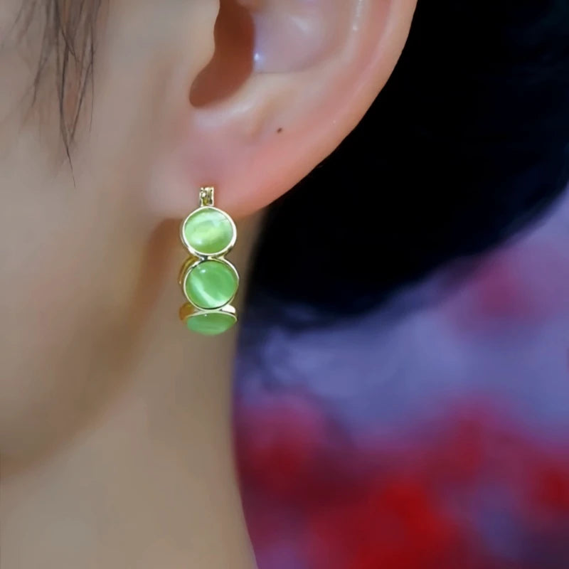 Model showcasing the dangle and style of the 14K Gold-Plated Elegant Cat's Eye Stone Hoop Earrings