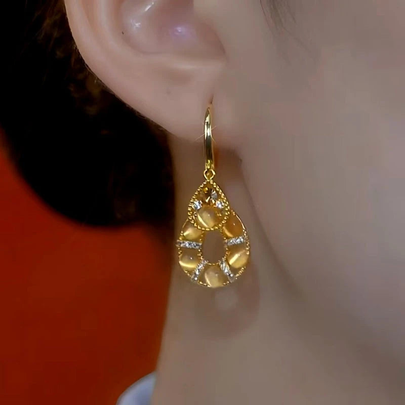 Model showcasing the dangle and style of the 14K Gold-Plated Elegant Cat's Eye Stone Water Drop Earrings