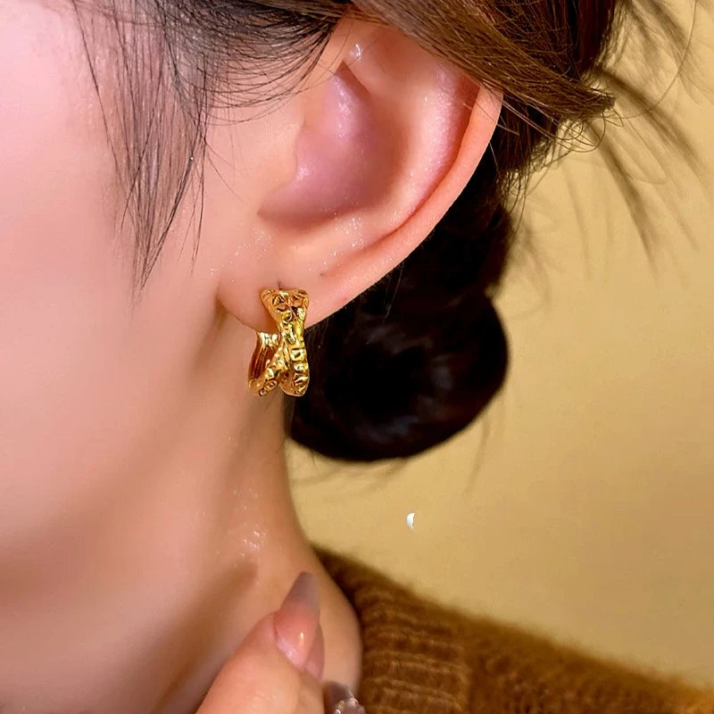 Model showcasing the dangle and style of the 14K Gold-Plated Elegant Cross-Gold Textured Earrings