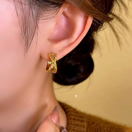 Model showcasing the dangle and style of the 14K Gold-Plated Elegant Cross-Gold Textured Earrings