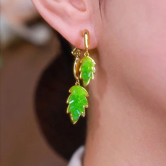 Model showcasing the dangle and style of the 14K Gold-Plated Elegant Crystal Leaf Cross Earrings