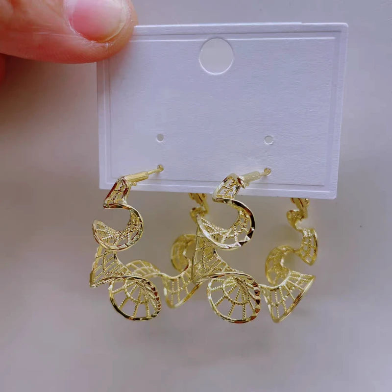 Model showcasing the dangle and style of the 14K Gold-Plated Elegant Curvy Hollow Lace Hoop Earrings