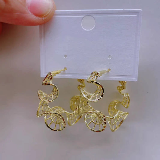 Model showcasing the dangle and style of the 14K Gold-Plated Elegant Curvy Hollow Lace Hoop Earrings