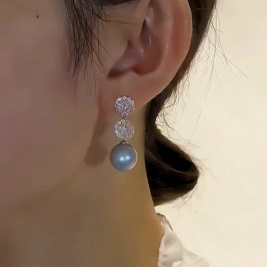 Model showcasing the dangle and style of the 14K Gold-Plated Elegant Diamond Blue Pearl Earrings