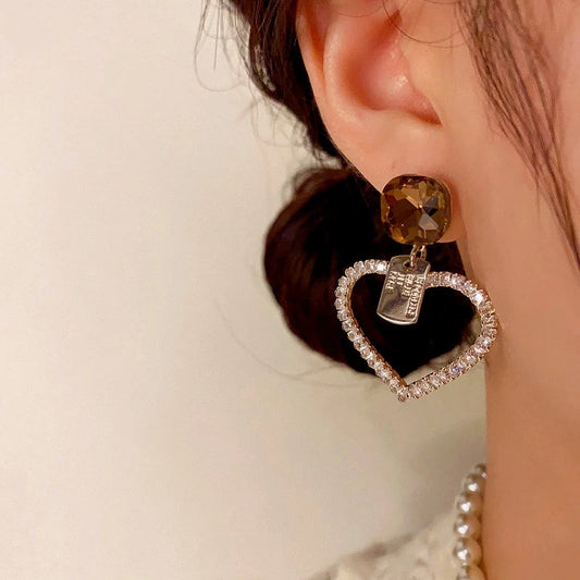 Model showcasing the dangle and style of the 14K Gold-Plated Elegant Diamond Heart Earrings