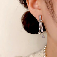 Model showcasing the dangle and style of the 14K Gold-Plated Elegant Diamond Knotted Water Drop Earrings