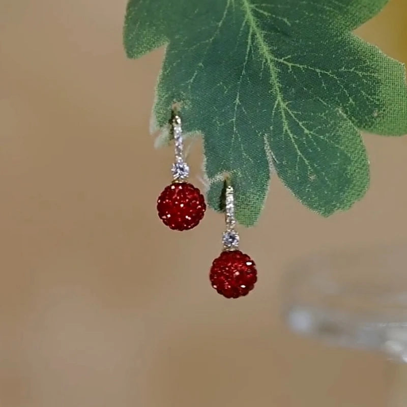 Angled view of the 14K Gold-Plated Elegant Diamond Red Ball Earrings