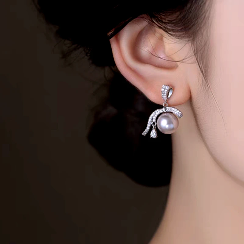 Model showcasing the dangle and style of the 14K Gold-Plated Elegant Diamond Ribbon Pearl Earrings