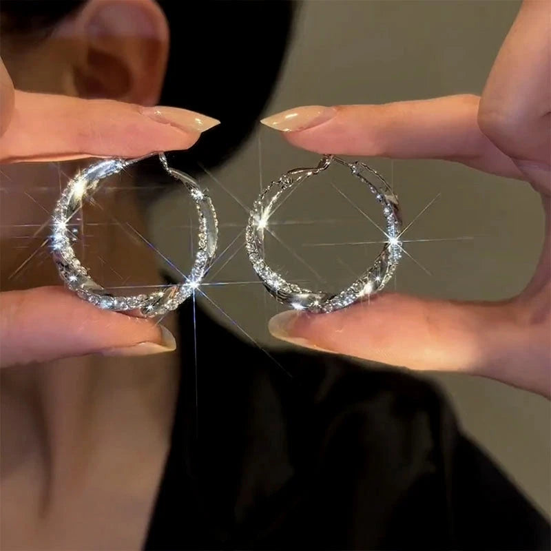 Model showcasing the dangle and style of the 14K Gold-Plated Elegant Diamond Twisted Hoop Earrings