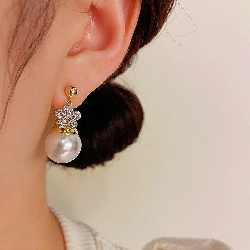 Model showcasing the dangle and style of the 14K Gold-Plated Elegant Double-Sided Flower Pearl Earrings