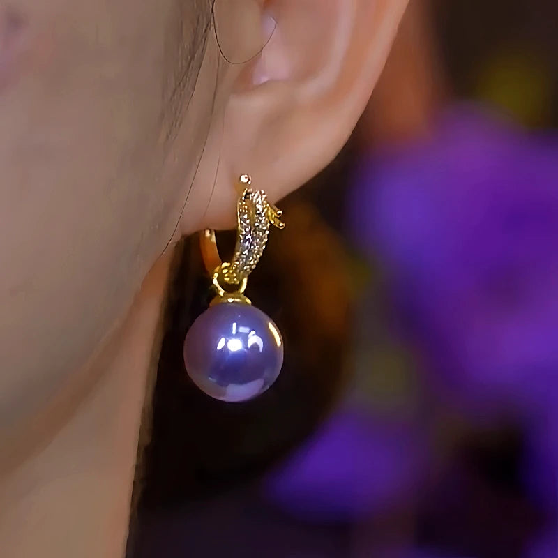 Model showcasing the dangle and style of the 14K Gold-Plated Elegant Dragon-Shaped Diamond-Studded Pearl Earrings