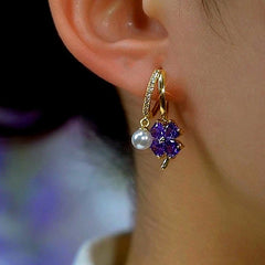 Model showcasing the dangle and style of the 14K Gold-Plated Elegant Purple Four-Leaf Flower Pearl Earrings